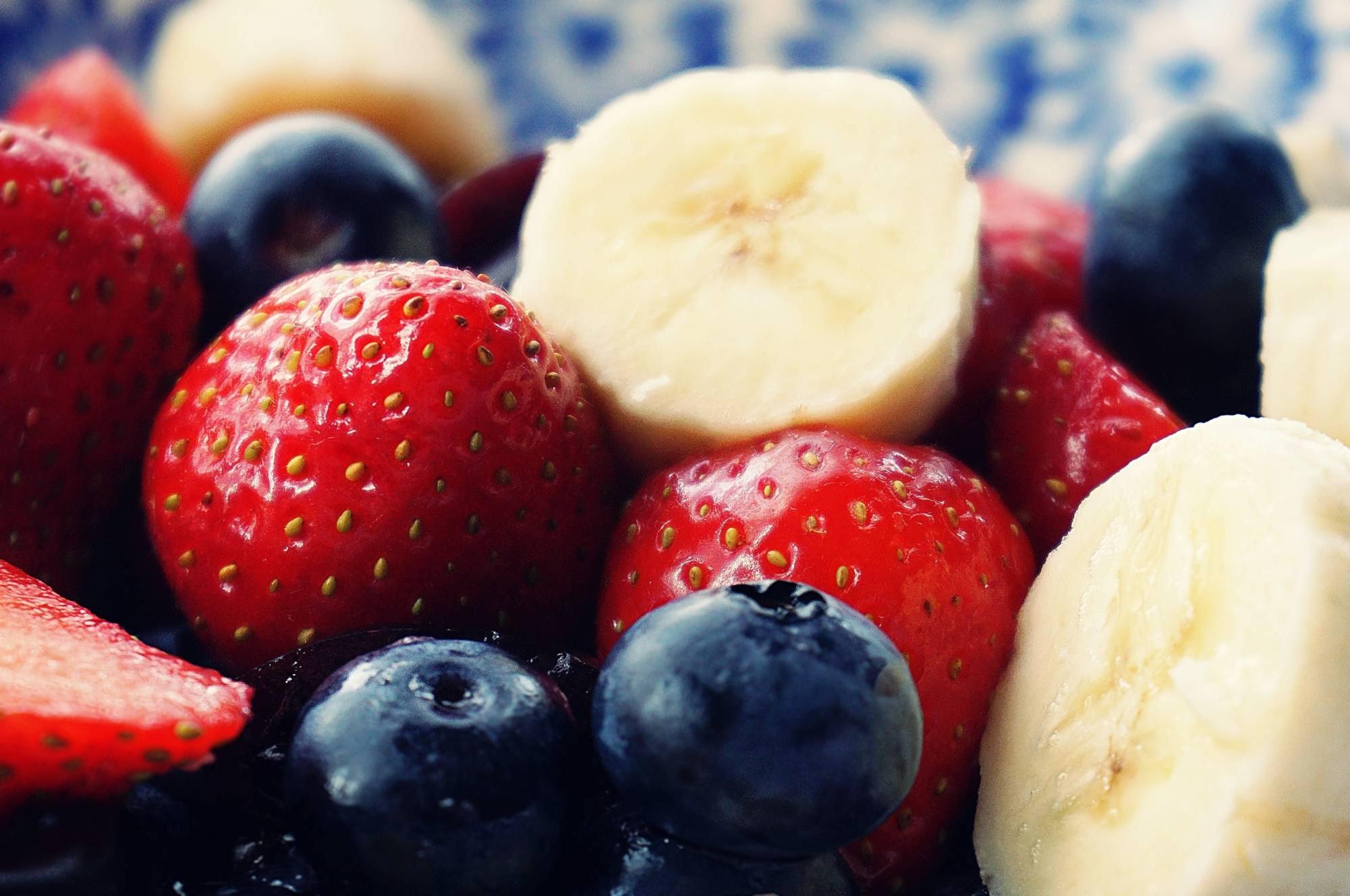 Bananas, strawberries, and blueberries sitting on a picnic table